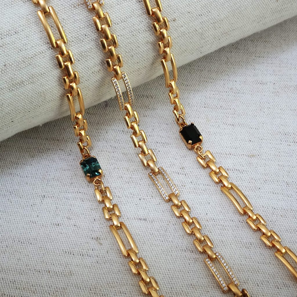 three link chain bracelets in gold with different center stones. a green stone, pave crystal design and black stone. feminine, petite, dainty bracelets